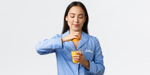 Woman squeezing orange juice into a cup to increase her Vitamin C intake.